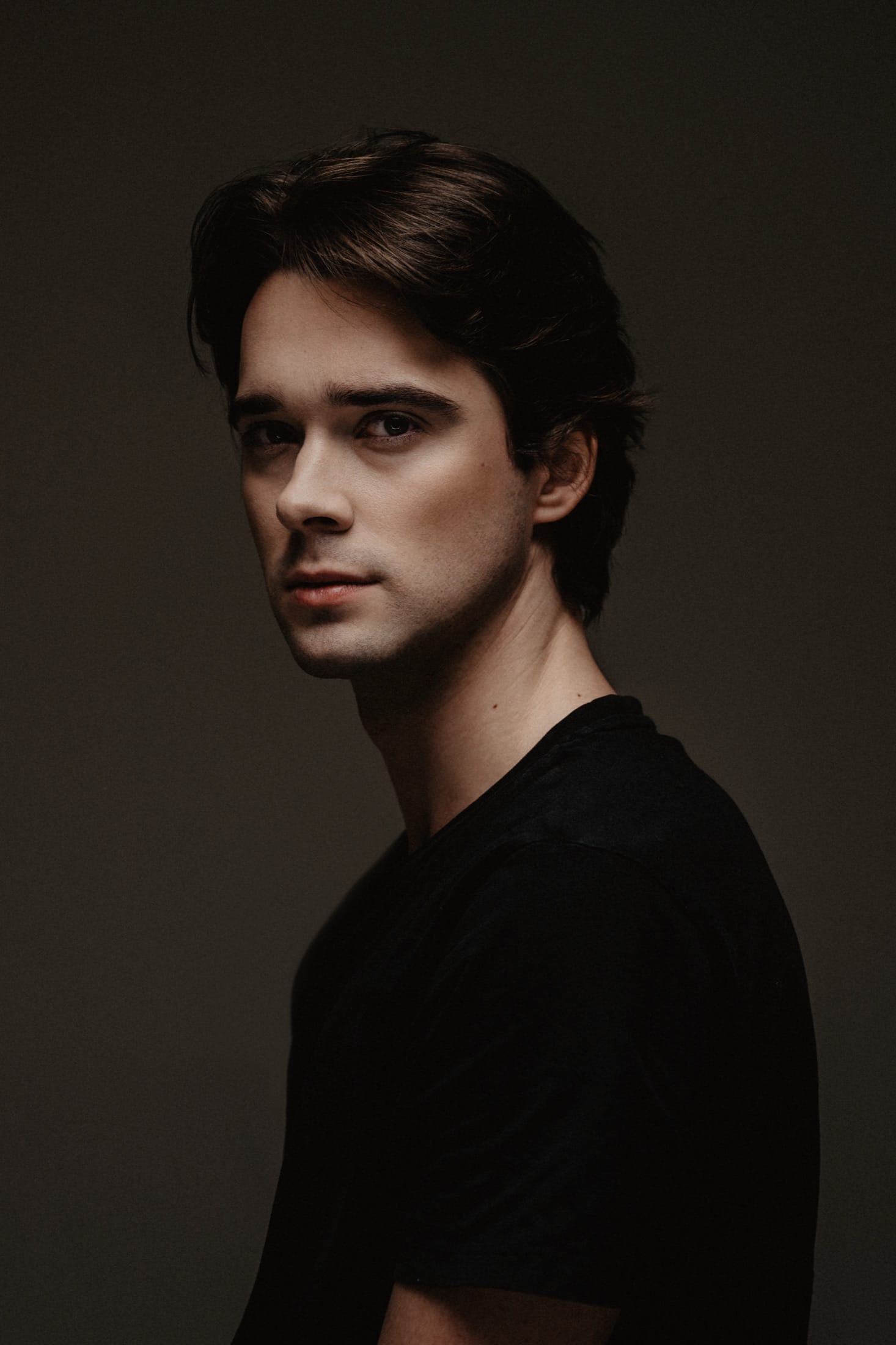Portrait of Vojtěch Babišta in a black t-shirt against a dark studio background